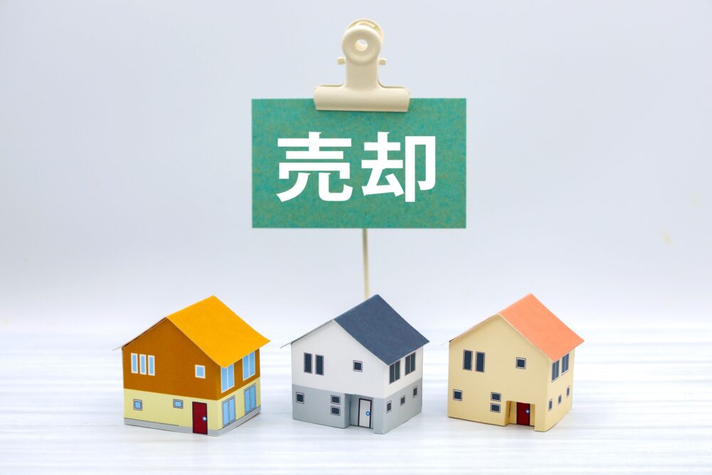 一戸建ての模型に売却のプラカードが刺さっている写真