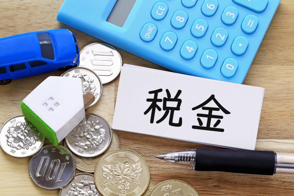 電卓と硬貨の上に税金と書かれた札が置いてある写真